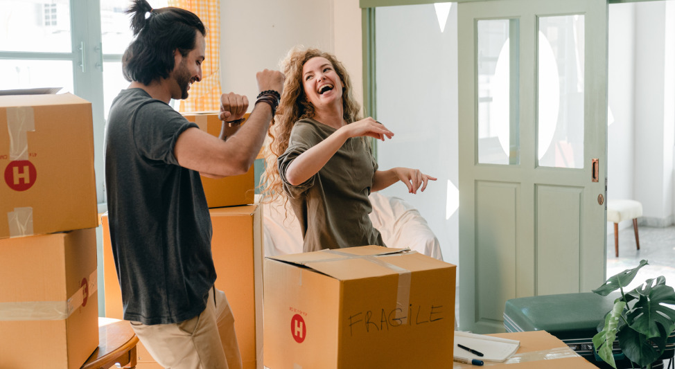 Man and woman having fun while packing items into storage boxes