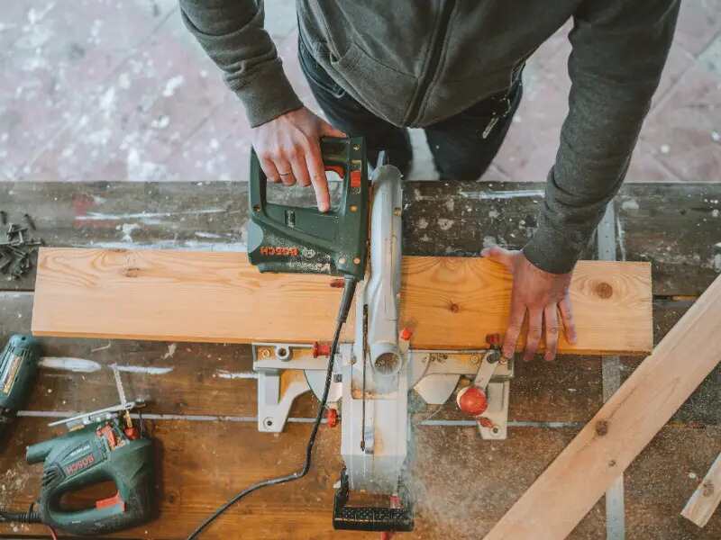 A Man Cutting Wood Using an Electric Jigsaw