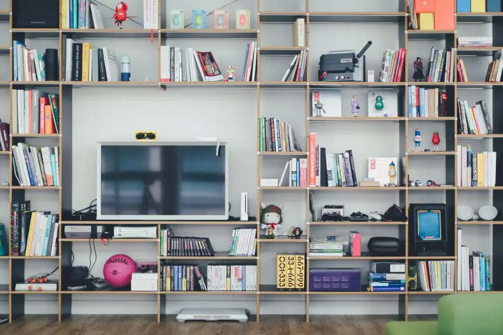 Book shelf filled with lots of books, TV, games and decorations