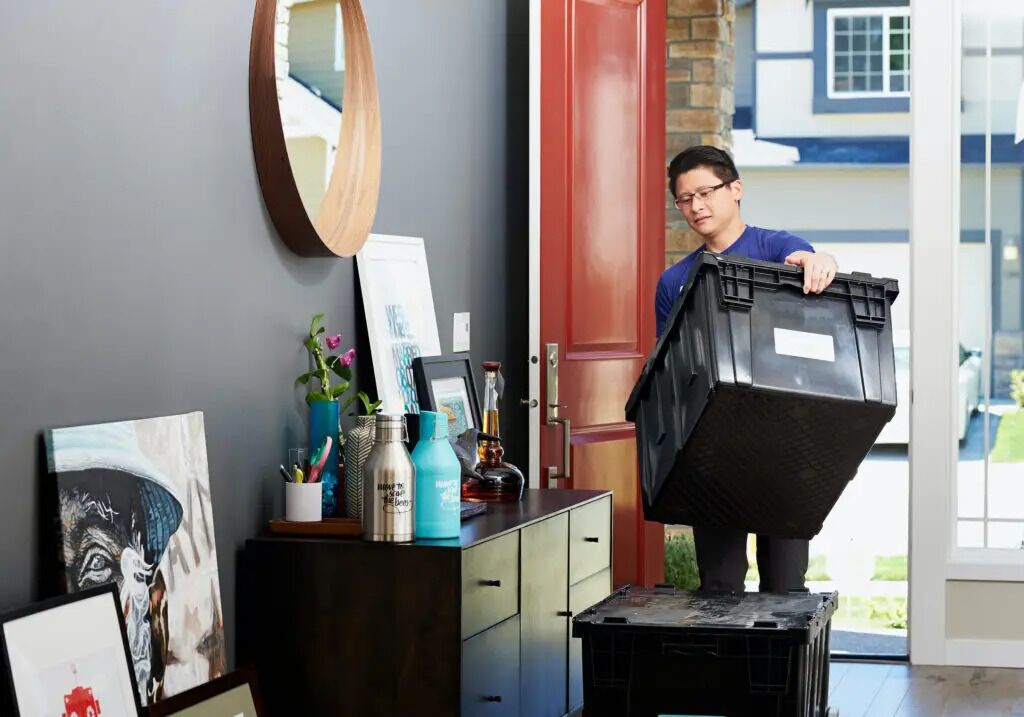 Student carrying black storage boxes through hallway